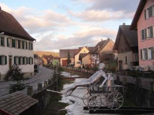 Hans Russenberger's latest public sculpture, 'de Laaterwägelibueb' spans the village creek. Russenberger was one of 30 artists to display at Scheitheim's art show. 